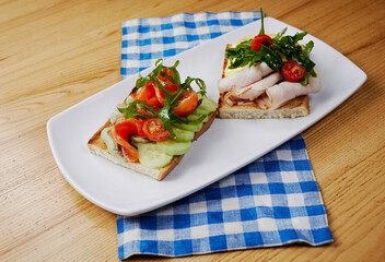 two sandwiches with salmon and avocado, ham and cheese and tomatoes