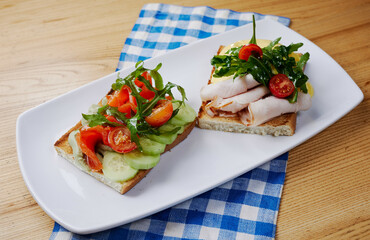 two sandwiches with salmon and avocado, ham and cheese and tomatoes