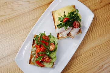 two sandwiches with salmon and avocado, ham and cheese and tomatoes