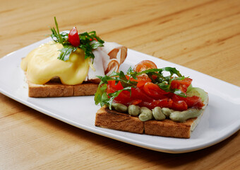 two sandwiches with salmon and avocado, ham and cheese and tomatoes