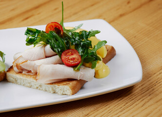 two sandwiches with salmon and avocado, ham and cheese and tomatoes