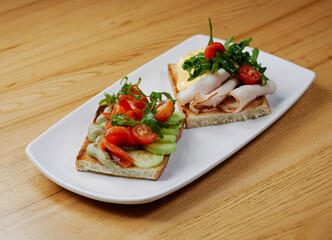 two sandwiches with salmon and avocado, ham and cheese and tomatoes