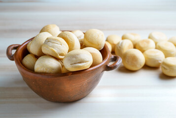 bread balls in a rustic ceramic container on a light wood base