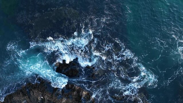 Aerial view of waves and clifs. Ocean waves breaking over rocks. Danger sea wave crashing on rock coast with spray and foam.