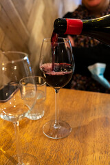 Pouring of dry Italian primitivo red wine in glass in Italian cantina restaurant in Puglia