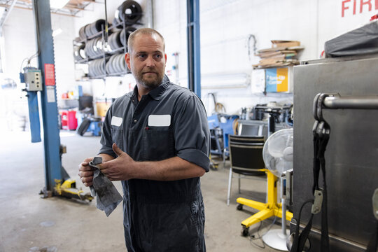 Mechanic Wiping Hands With Dirty Rag In Workshop