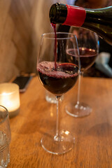 Pouring of dry Italian primitivo red wine in glass in Italian cantina restaurant in Puglia