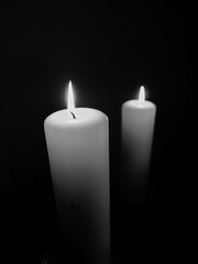 Vertical monochrome photo of two thick lit candles