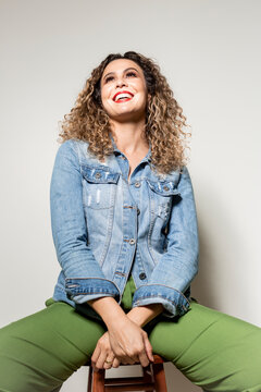 Studio shot of proud young girl with perfect light brown skin and beautiful curly hair in empowerment pose on a white background.
