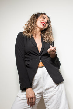 Studio shot of proud young girl with perfect light brown skin and beautiful curly hair in empowerment pose using a lipstick on a white background.
