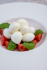 Tasty caprese salad with cherry tomatoes, white mozzarella cheese and green basil leaves