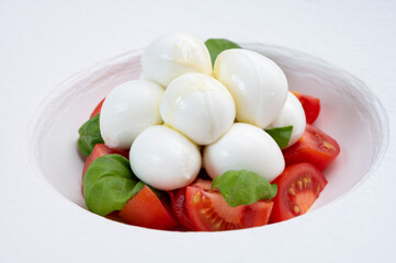 Tasty caprese salad with cherry tomatoes, white mozzarella cheese and green basil leaves