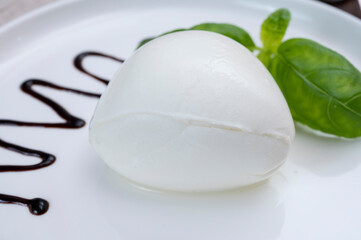 Fototapeta premium Tasing of fresh italian cheese mozzarella di buffalo with Balsamic vinegar from Modena