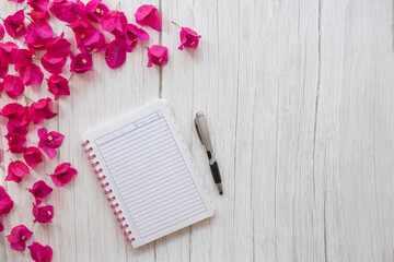 Libreta rayada en mesa de madera y flores de bugamilia