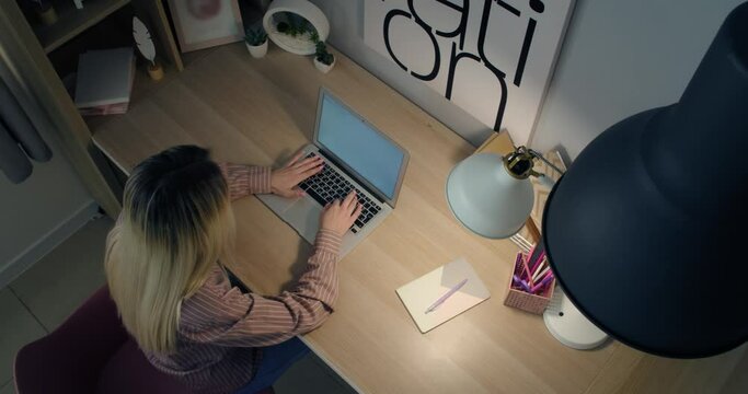 Young woman working on laptop at table, top view