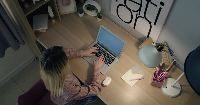 Young woman working on laptop at table, top view