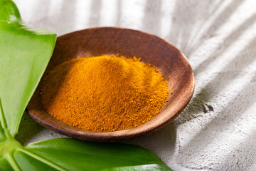 Turmeric powder, in wooden bowl and spoon