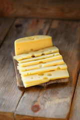 Selective focus. Macro. Cheese with holes slices on a wooden surface.