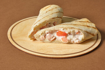 cut roll with chicken on a tray on a brown background, copy space, stuffing in pita bread, fast food concept
