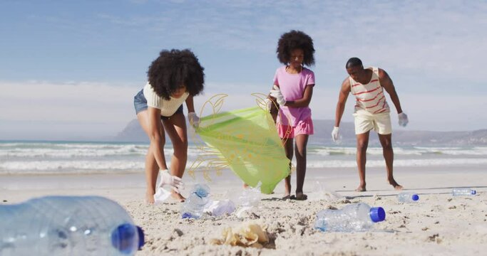 Animation of cancer over diverse female and male volunteers picking up rubbish on beach