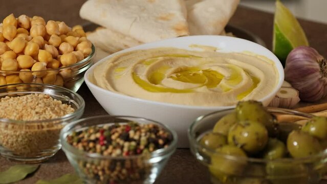 Chickpea hummus made from mashed chickpeas dip with tahini lemon garlic and olive oil close-up. Enjoying yummy hummus with pita, lavash, bread sticks, grissini. Kosher healthy vegan food. Lean dish 