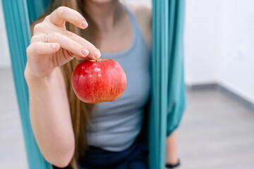 yogi fitness woman holds an apple after a workout in hammock for yoga. the concept of healthy...