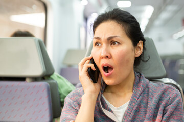 Outraged woman talking on mobile phone during subway ride