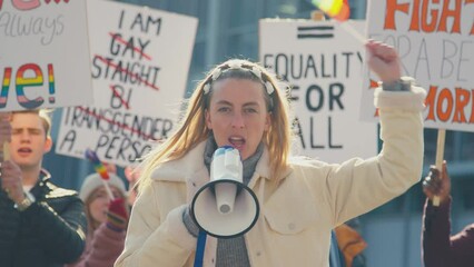 Group of protestors with megaphone holding placards and waving flags on demonstration march to promote gender equality- shot in slow motion