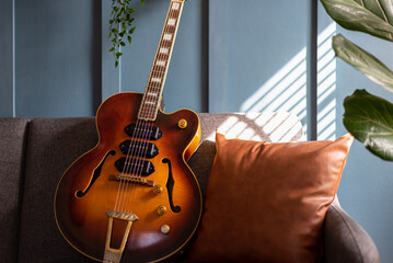 Vintage jazz guitar against a blue wall in natural light - 498391531