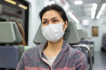 Portrait of young adult relaxed woman wearing face mask for prevent illness using urban train to commute