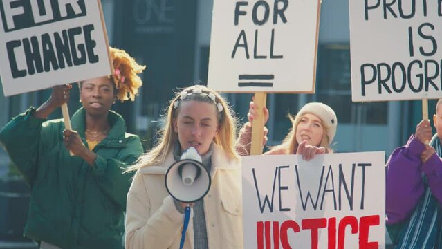 Group of protestors with megaphone holding placards and chanting slogans on demonstration march to promote black lives matter anti racist beliefs - shot in slow motion