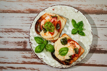 Top view of a Brusqueta with mozzarella caprese, tomato and hot basil. Traditional and mediterranean food concept.