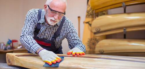 Senior man carpenter making wooden boat in his workshop