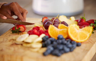 Preparing some healthy goodness to snack on. Closeup shot of an unrecognisable woman cutting fresh fruit at home.