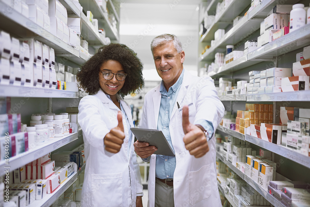 Poster we are on track with stock. portrait of two cheerful pharmacists holding a digital tablet and showin