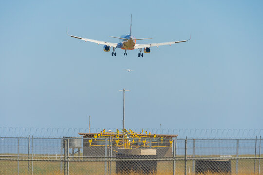 Rear view of a large jet coming into land over runway landing lights and fences