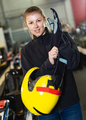 Portrait of fine woman holding helmet at kart circuit