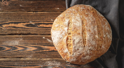 Homemade natural bread with a Golden crust on a napkin on an old wooden background. Baking bakery products. Rustic style