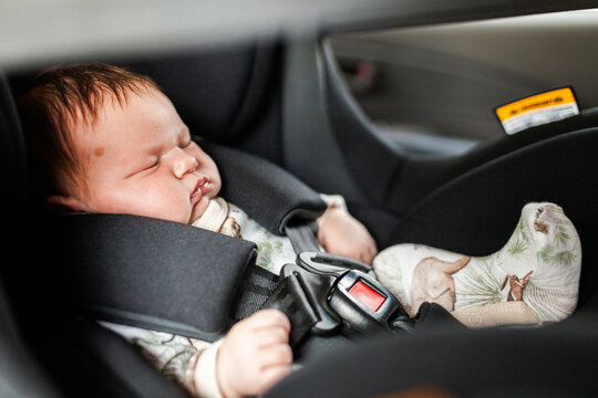 sleepy newborn baby strapped into car seat - safety
