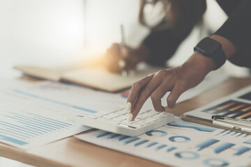 Asian Business Woman or Accountant do math and analyze with calculator and paperwork on desk, account, consult, audit and saving concept.