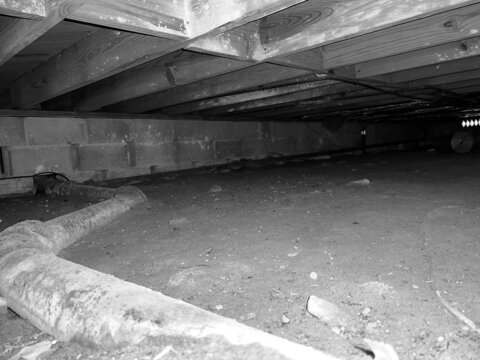 Pipe Running in Dirt Crawl Space Under House Grayscale