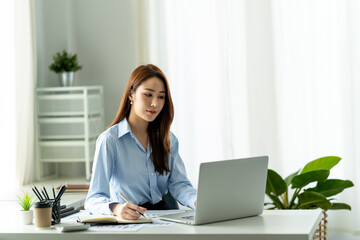 Beautiful young Asian girl working at a office space with a laptop. Concept of smart female business.