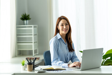 asian businesswoman sitting working on laptop in office.