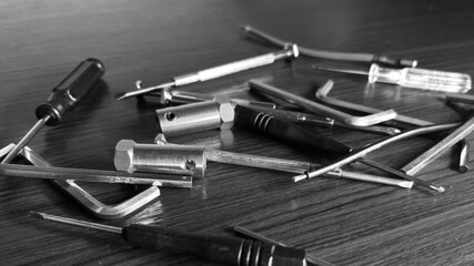 Pile of Tools on Wooden Table with Allan Wrenches Screwdrivers, Wires, Hub Caps for Motors Grayscale