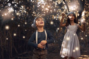 The fireflies have come out to play. Shot of two little siblings catching fireflies in jars outside.