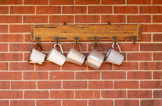Fototapeta white and silver tin mugs hanging on red brick wall