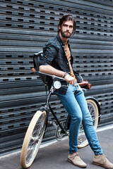 Hes definitely a trendsetter. Full length shot of a handsome young man sitting on a bicycle outdoors. - obrazy, fototapety, plakaty