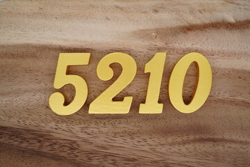 Golden Arabic numerals on a real brown and white wooden floor number 5210