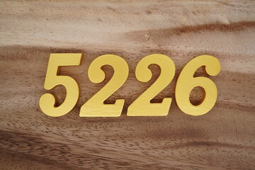 Golden Arabic numerals on a real brown and white wooden floor number 5226