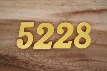 Golden Arabic numerals on a real brown and white wooden floor number 5228